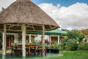 una mesa y sillas bajo un techo de paja en York Lodge, en Harare