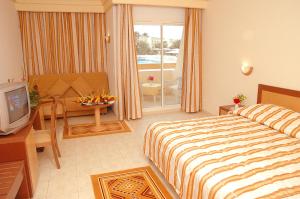 a hotel room with a bed and a television at El Mouradi Tozeur in Tozeur