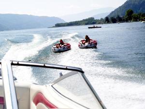 two people are riding in boats on the water at FeWo mit Seeblick in Bodensdorf