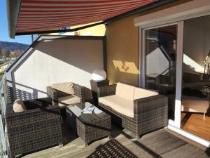 a balcony with wicker chairs and a couch and a table at FeWo mit Seeblick in Bodensdorf