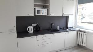 cocina con armarios blancos, fregadero y ventana en Anykščiai Center Apartment, en Anykščiai