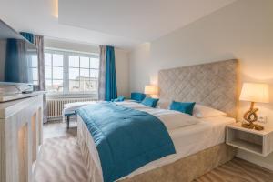 una camera da letto con un grande letto con cuscini blu di Hotel Garni Kölfhamm a Sankt Peter-Ording