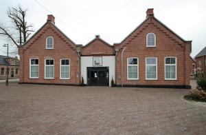 un gran edificio de ladrillo con una puerta grande en Hotel Aan De Singel, en Delfzijl