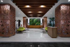 un vestíbulo de un hotel con paredes de madera y sillas verdes en The Alana Hotel and Conference Sentul City by ASTON, en Bogor