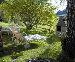 a white bench sitting in the grass in a yard at Studio in Chasa Quirin in Zernez