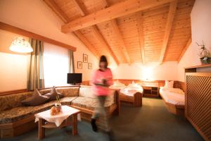 a woman running through a living room with a couch at Villa Rier in Siusi