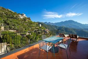 een balkon met een tafel en stoelen en bergen bij Casa Rossa in Ravello