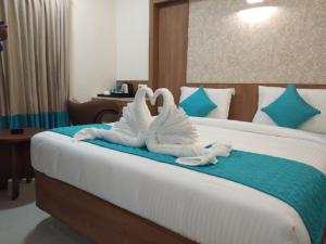 two swans folded towels sitting on top of a bed at Hotel iStay in Coimbatore