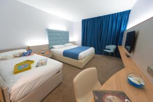 um quarto de hotel com duas camas e uma mesa e uma televisão em Hotel Plaza - site du Futuroscope em Chasseneuil-du-Poitou