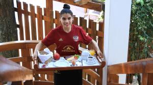 una mujer sosteniendo una bandeja de comida en una mesa en Hotel Westfalenhaus, en Asunción