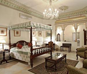 ein Schlafzimmer mit einem Himmelbett und ein Wohnzimmer in der Unterkunft Alsisar Haveli - Heritage Hotel in Jaipur