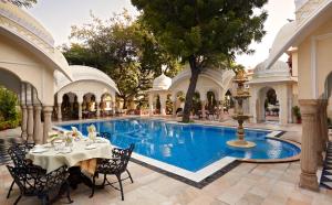 einen Pool im Innenhof mit einem Tisch und Stühlen in der Unterkunft Alsisar Haveli - Heritage Hotel in Jaipur