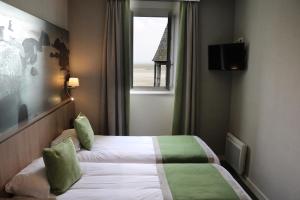 une chambre d'hôtel avec un lit et une fenêtre dans l'établissement Le Mouton Blanc, au Mont-Saint-Michel