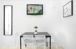 a dining room table with white chairs and a tv on the wall at Maksimir-Rebro in Zagreb