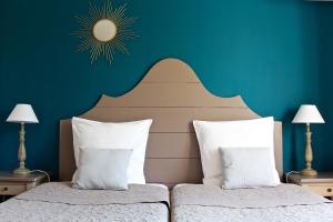 Schlafzimmer mit einem Bett mit blauer Wand in der Unterkunft Hotel Les Oliviers in Draguignan