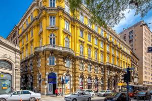 un edificio amarillo con coches estacionados frente a él en Number 1 Deluxe Apartments, en Rijeka