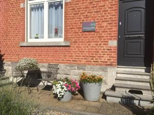 une maison avec trois pots de fleurs devant une porte dans l'établissement B&B Au Jardin Fleuri, à Marche-en-Famenne