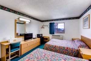 a hotel room with two beds and a desk and a mirror at 9 Motel in Fort Collins