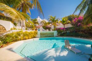 una piscina con una silla y una casa en Villas Fasol Huatulco, en Santa Cruz Huatulco