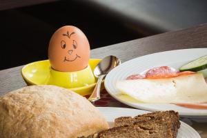 un œuf avec un visage tiré à côté des assiettes de nourriture dans l'établissement Saaletal Pension & Ferienwohnungen, à Bad Bocklet