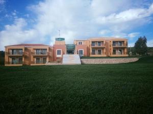 un grand bâtiment avec une pelouse devant lui dans l'établissement Finiki Plaza, à Methoni