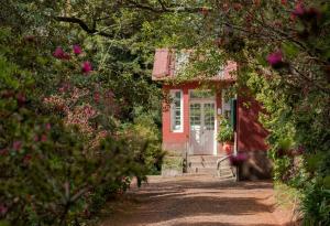 een rood huis met een witte deur en wat bloemen bij Quinta Santo Antonio Da Serra in Santa Cruz