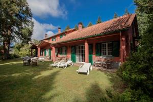 een rood huis met stoelen en tafels in de tuin bij Quinta Santo Antonio Da Serra in Santa Cruz