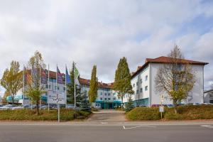 a large white building on the side of a street at H+ Hotel Stuttgart Herrenberg in Herrenberg