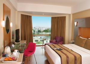 a hotel room with a bed and a desk and a window at The Golkonda Hotel in Hyderabad