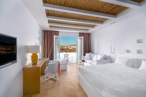 een witte slaapkamer met een bed, een bureau en een bank bij Cape Mykonos in Mykonos-stad