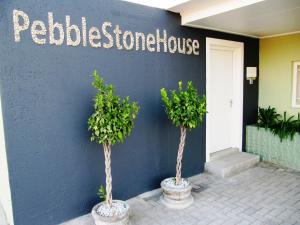 Pebble Stone House في سواكوبموند: شجرتين في قدور أمام مبنى أزرق