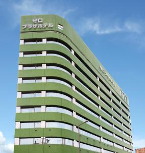 un edificio alto e verde con un cartello sopra di Osaka Moriguchi Plaza Hotel ad Osaka