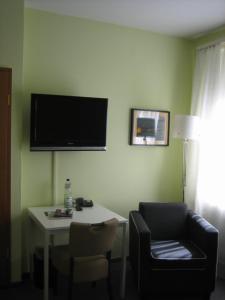 a room with a table and a chair and a television on the wall at BSW Ferienhotel Lindenbach in Bad Ems