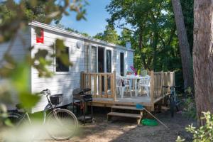 una casa pequeña con una mesa y sillas en el porche en Camping Officiel Siblu le Montourey, en Fréjus