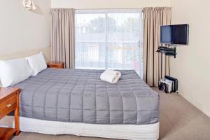 um quarto com uma cama e uma grande janela em Tourist Court Motel em Whakatane