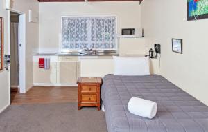 um pequeno quarto com uma cama e uma cozinha em Tourist Court Motel em Whakatane