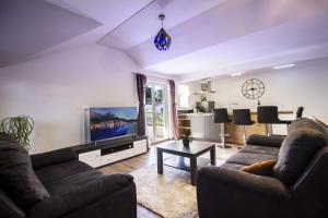 uma sala de estar com 2 sofás e uma televisão de ecrã plano em Apartments Dvor - ap1, ap2, ap3 em Baška Voda