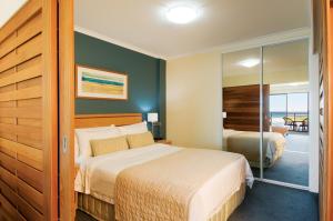 Tempat tidur dalam kamar di Oaks The Entrance Waterfront Suites