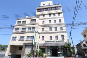 um edifício branco alto na esquina de uma rua em Business Hotel Sansei em Saiki