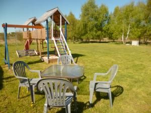 un tavolo con sedie e un parco giochi in un campo di Cztery Pory Roku a Trzęsacz