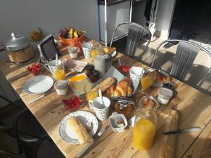 uma mesa com pequeno-almoço de pão e sumo de laranja em Ma Maison em Beaune