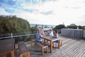 une famille assise à une table en bois sur une terrasse dans l'établissement YHA Apollo Bay Eco, à Apollo Bay