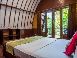 1 dormitorio con 1 cama grande y ventanas en Gili Turtle Beach Resort, en Gili Trawangan