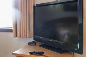 una TV a schermo piatto seduta su un tavolo con telecomando di El Rancho Hotel a Williston