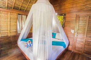 un letto con zanzariera in una camera di Lotus Garden Huts a Nusa Lembongan