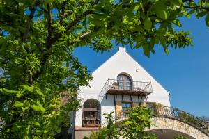 uma casa branca com varanda e árvores em Figula Vendégház em Balatonfüred