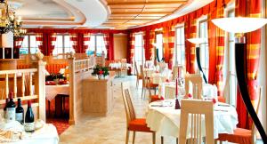 a restaurant with tables and chairs and red curtains at Hotel Chalet Tianes - Alpine Relax in Castelrotto