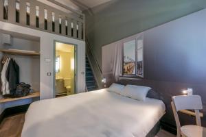 a bedroom with a large white bed and a chair at B&B HOTEL Montauban in Montauban