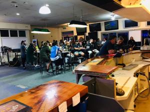 un groupe de personnes assises à des tables dans une pièce dans l'établissement The Kamo Hotel, à Whangarei