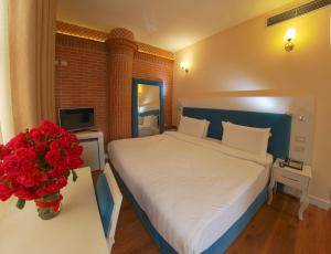 a bedroom with a bed and a vase of red flowers at The Red Bricks Hotel in Shkodër